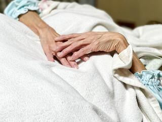 Obraz na płótnie Canvas 白い毛布をかけて寝る高齢女性の手