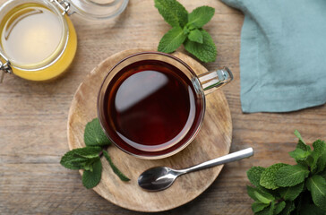 Cup of hot aromatic tea with mint and honey on wooden table, flat lay