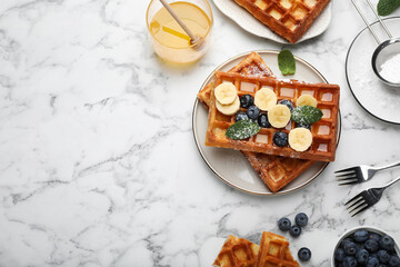 Delicious Belgian waffles and ingredients on white marble table, flat lay. Space for text