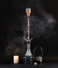 hookah with glass flask and earthenware bowl with smoke on black background.Traditional oriental rest for  relaxation