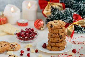Homemade crunchy cranberry cookies with white chocolate and fresh berry. Delicious healthy dessert. Christmas. New Year. Candles, garlands and Christmas tree toys. Selective focus
