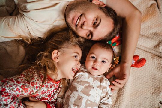 happy beautiful family laughing lying on the carpet, new year mood, daddy playing with children, cute little girl laughing and little boy baby x mas eve celebration