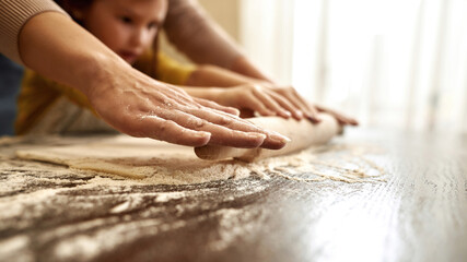 Obraz na płótnie Canvas Close up of girl and grandmother rolling out dough