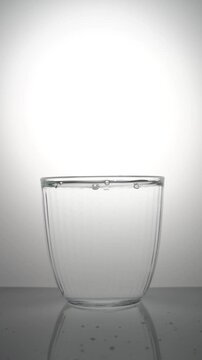 Water drips from above into a clear glass.