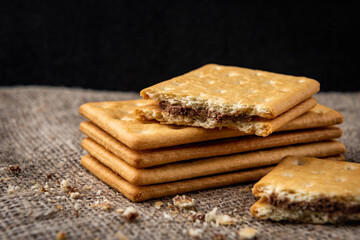 Cracker sandwiches with chocolate filling on black background.