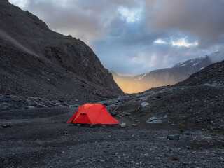 Surrealist alpine landscape with tent on rocky hill among rocks in sunrise. Beautiful morning...