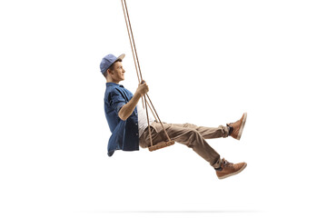 Profile shot of a young man swinging on a wooden swing - obrazy, fototapety, plakaty