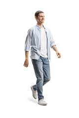 Full length shot of a happy young man in jeans and shirt walking