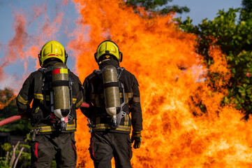 firefighters wearing fire fighter suit for safety and using twirl water extinguisher for fighting...