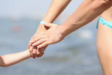 Family holding hands, mother father and child walking on coastline