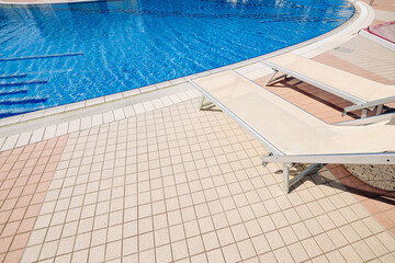 Lounge pool. Summer resort chair, relax lounge at luxury hotel pool. Beach lounger chaise. Vacation sunbed. Blue water, sunny happy travel holiday.