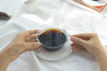 woman's hand holding a glass coffee cup.