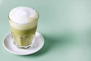 Matcha green tea latte in t glass on Green background Healthy Drink Copy Space Horizontal