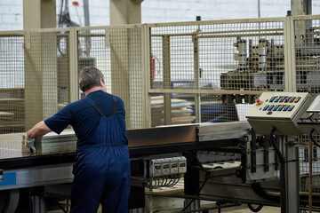 A worker processes furniture blanks on a machine tool in a factory. Industrial production of furniture.