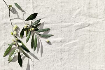 Foto auf Glas Olive branch with olive fruits on linen background. Mockup for concept of wellbeing, skincare, beauty or healthy lifestyle. © Caterina Trimarchi