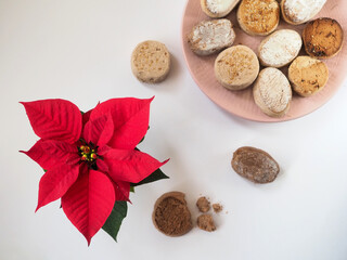 Plate with Spanish Christmas cookies Estepa, Polvoron, Mantecado, Nevaditos and Poinsettia flower on white background. Flat lay