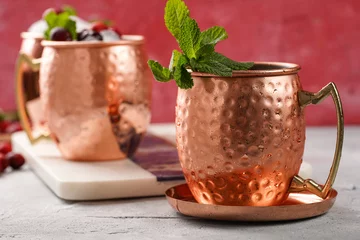 Fototapete Rund Traditional american alcoholic beverage moscow mule in copper mugs with cranberry and mint on white marble board - non-alcoholic cocktail version © Romana