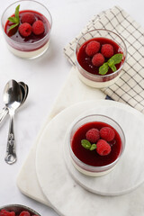 Italian dairy dessert panna cotta with raspberry jam and fresh raspberries on marble board