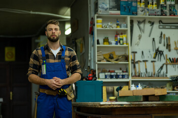 portrait of young caucasian male carpenter posing for camera in workshop
