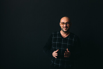 a young man, businesslike, sociable speaker, says something with gestures. in the studio on a black background.