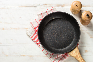 Frying pan or skillet with sea salt and pepper on white wooden table. Top view with copy space.