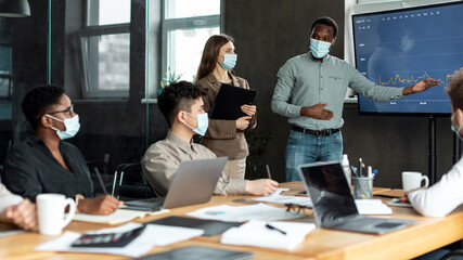 Colleagues having meeting in boardroom, businessman showing graph
