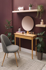 Wooden dressing table and chair near brown wall in room