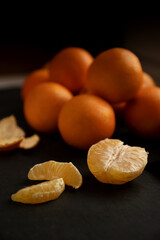 Naklejka na ściany i meble Half of peeled tangerine with some slices on group of ripe tangerines background