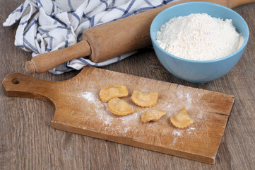 Préparation de raviolis sur une planche à découper  avec un bol de farine et un rouleau à pâtisserie