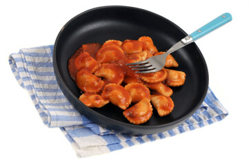 Assiette de raviolis avec une fourchette posée sur un torchon à carreaux en gros plan sur fond blanc