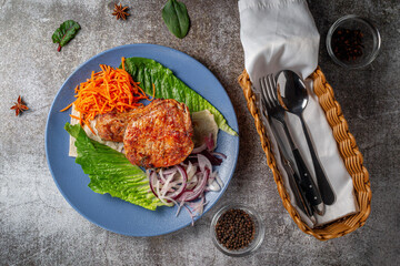 Serving a dish from the restaurant menu. Grilled beef and pork meat with grated carrots and herbs on a plate against a gray stone table, delicious kebab