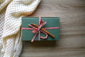 Two hardcover books wrapped with ribbon, candy cane and cinnamon stick and soft knitted blanket....