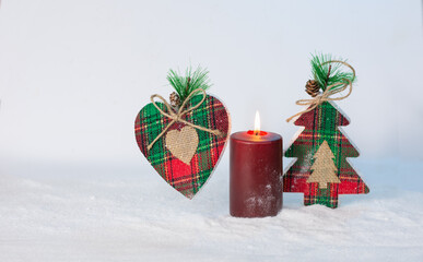 Christmas composition: handmade heart and candle on the background of a toy Christmas tree. Selective focus