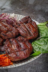 Serving a dish from the restaurant menu. Grilled beef and pork meat with grated carrots and herbs on a plate against a gray stone table, delicious kebab