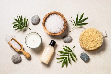 Fototapeta na wymiar Spa background. Spa product composition with palm leaves, cosmetic and sea salt at stone table. Flat lay image.