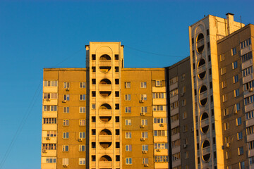 Kyiv, Ukraine. May 1, 2020. Typical façade of paneled, high-rise communal building against a blue sky at sunset. Terrible ugly architecture in post-Soviet countries. An old urban houses with windows.