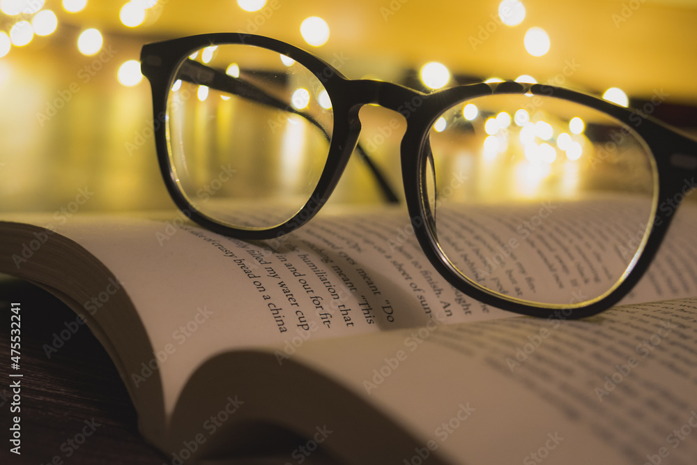 Sticker closeup shot of a reading glass on an opened book against bokeh lights