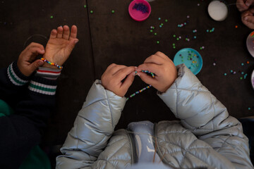 little children's hands weave a bead bracelet close-up shot