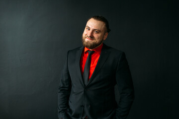 young man, business, sociable speaker, businessman, in a suit with a red shirt, in the studio on a black background.