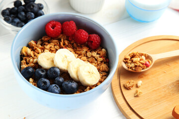 Granola with fruit on a white background. Granola with raspberries, blueberries and banana