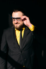 Obraz premium young man, business, sociable speaker, businessman, in a suit with a yellow shirt, in the studio on a black background.