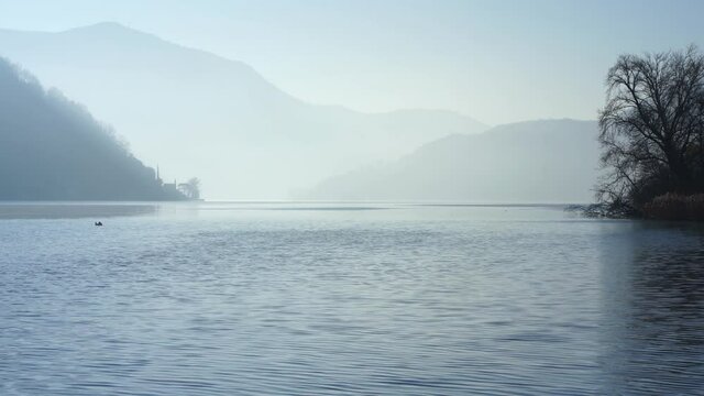 Sunrise at Lake Lugano in autumn winter with light fog. 