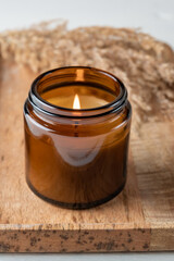 Burning aroma candle in a glass jar with the aroma of spices. Autumn atmosphere with dry reeds...