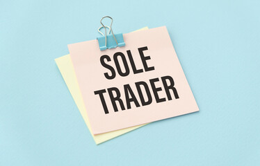SOLE TRADER, text on white paper on gray background near money.