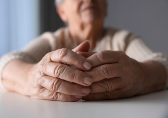 Elderly woman at white table indoors, closeup