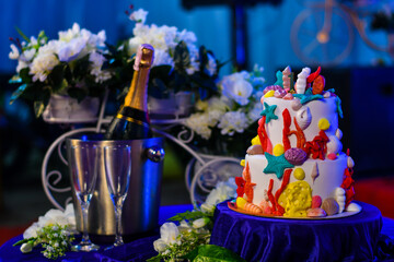 Ocean themed birthday cake with champagne and white flowers in the background