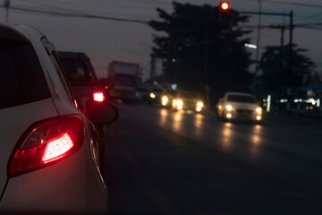 Cars on the road in traffic junction at night with red light signal.  There are many car on the road.