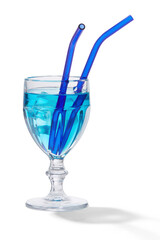 A light blue cocktail with ice cubes is in a wine glass with reusable translucent blue glass straws. The glass is isolated on the white background.