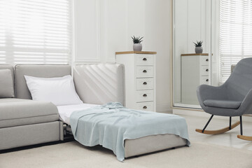 Stylish room interior with sleeper sofa and rocking chair. Additional place for guest
