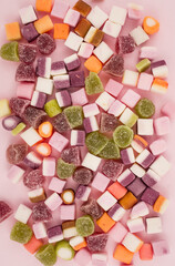 A large pile of mixed sweets on wooden background